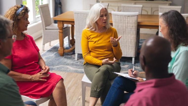 Caucasian senior woman talking with multiracial people at group therapy session. unaltered, support, alternative therapy, community outreach, mental wellbeing and social gathering.