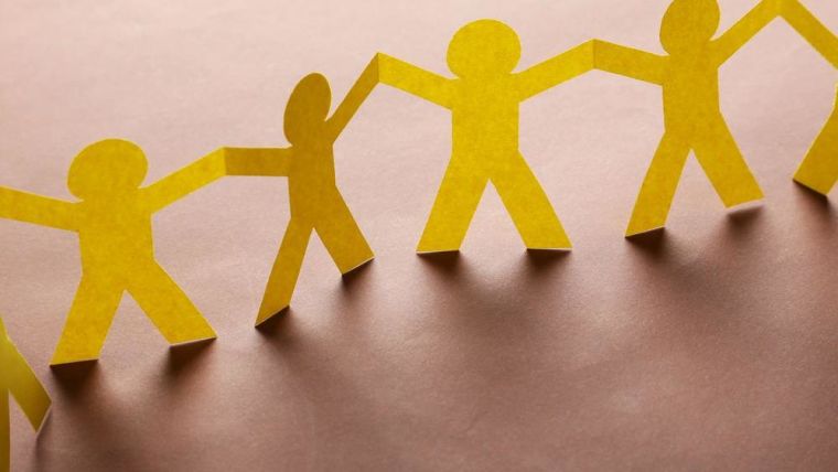 close up of yellow paper cut-out men holding hands